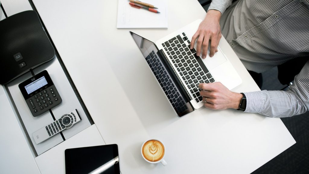 person using laptop on white wooden table